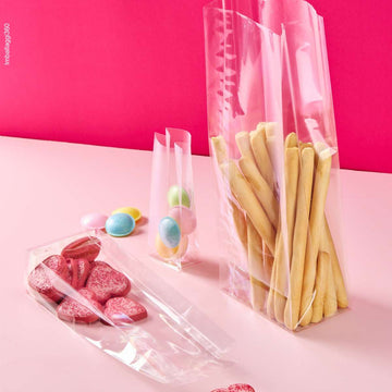 Sacchetto trasparenti a fondo quadro, ripieni di dolci e grissini, varie misure, su sfondo rosa